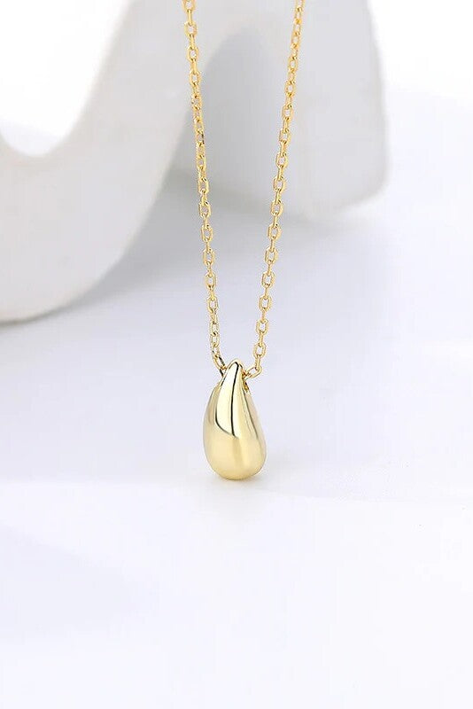 Gold necklace with a teardrop pendant on a white background