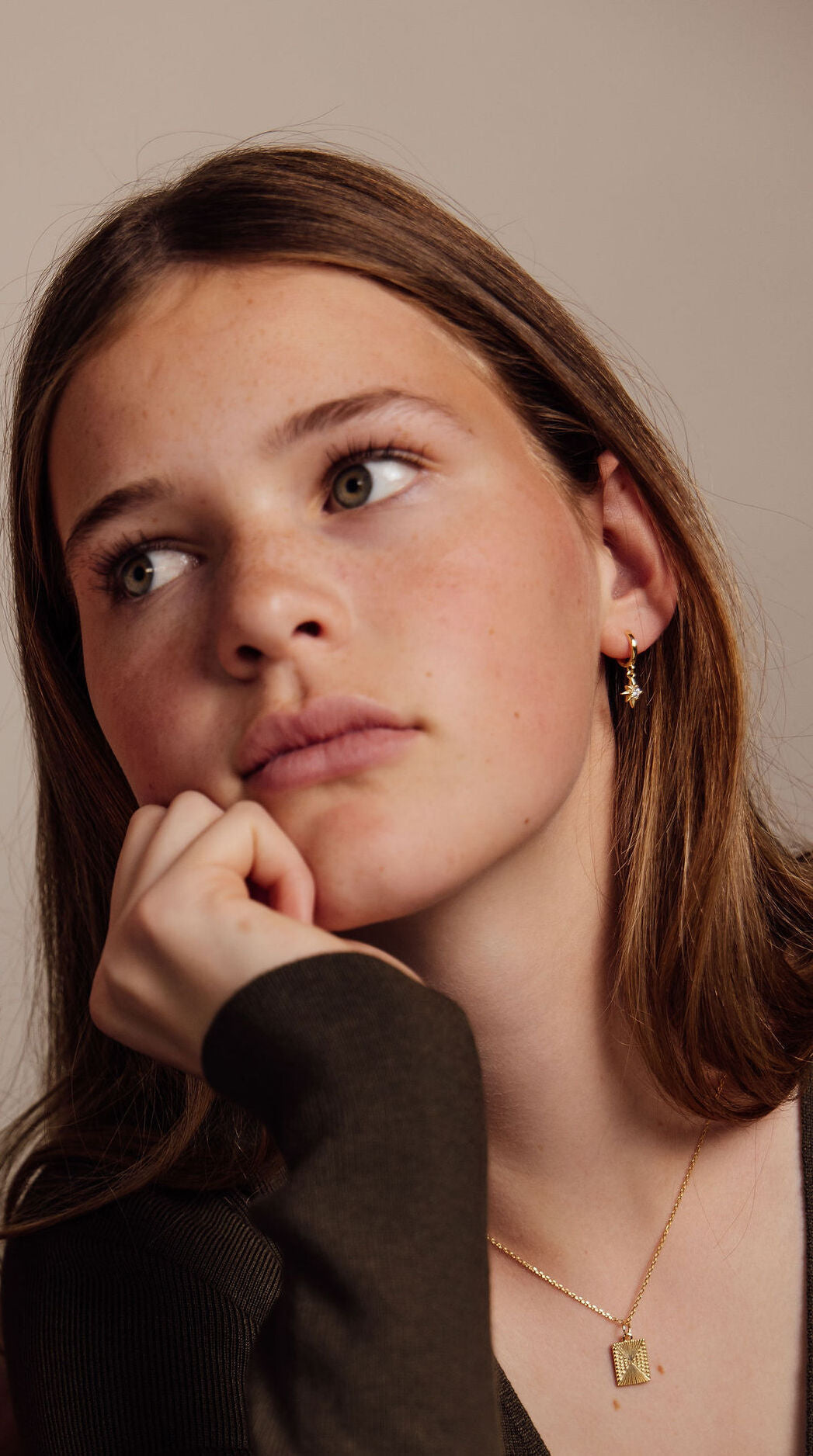 Woman wearing a gold necklace and gold earrings