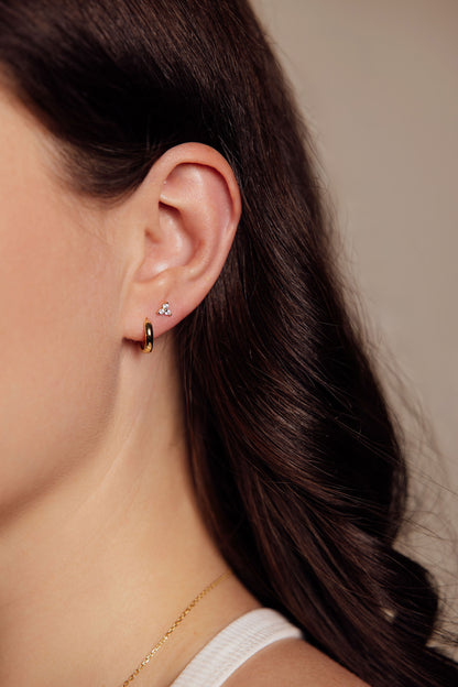 Close-up of a woman wearing gold earrings with a neutral background