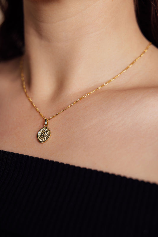 Close up of a gold necklace on a woman wearing a black top