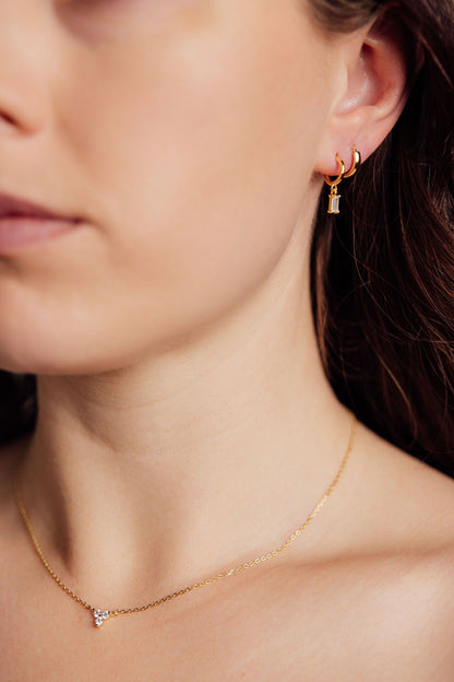 Close-up of a person wearing gold earrings and a gold necklace 