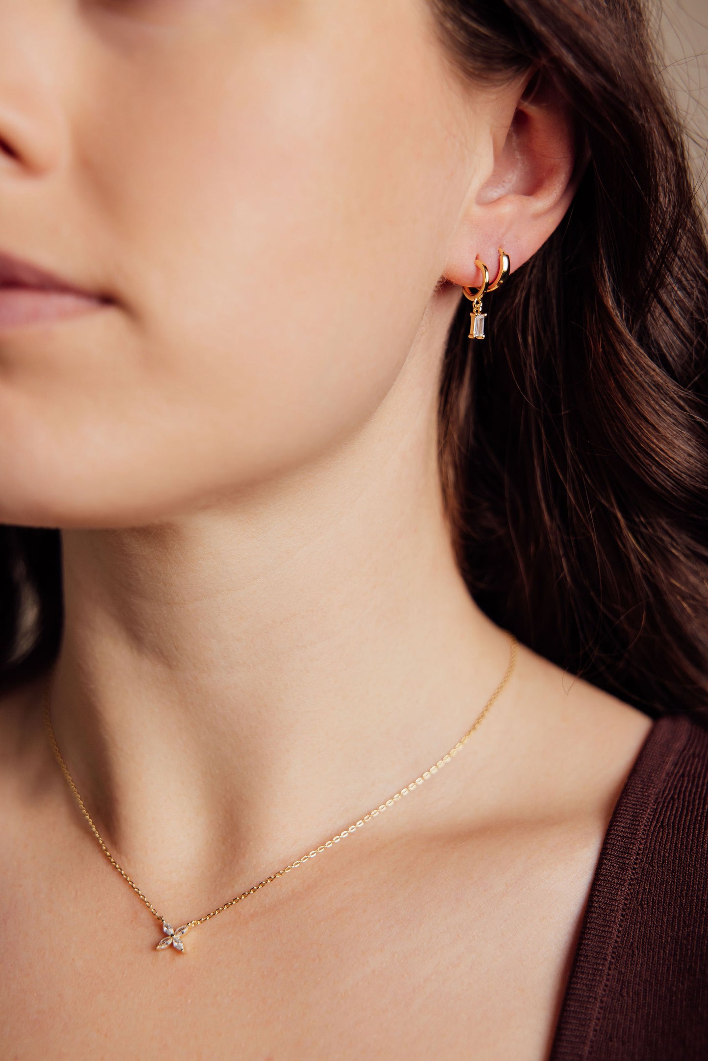 Close-up of a woman wearing gold earrings and a gold necklace.