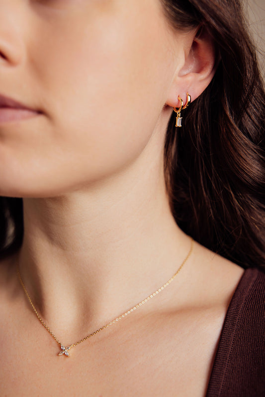 Close-up of a woman wearing gold earrings and a gold necklace.