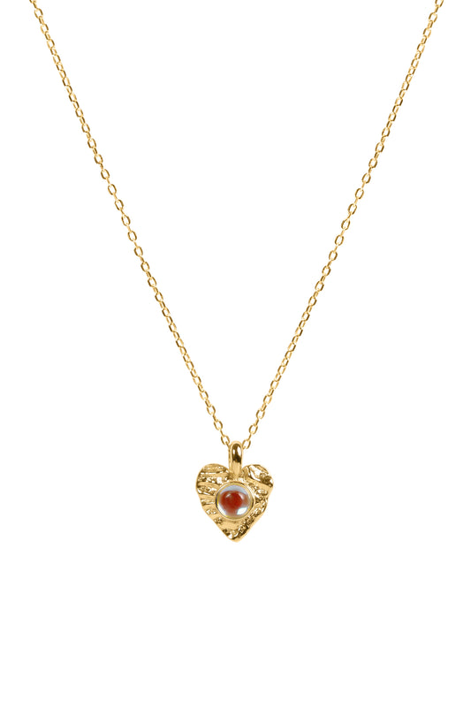 Gold necklace with a heart-shaped pendant featuring a moonstone on a white background