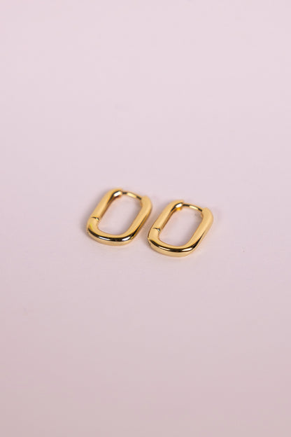 Gold oblong hoop earrings on a neutral background