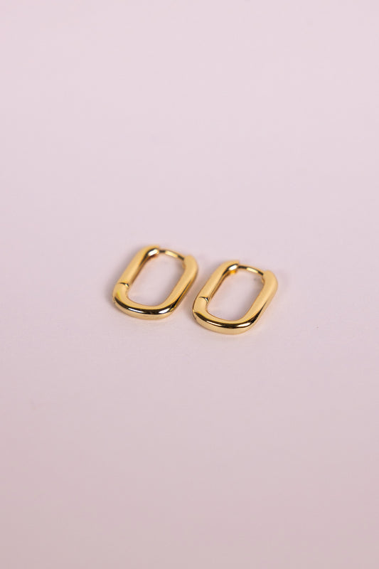 Gold oblong hoop earrings on a neutral background