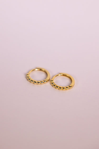 Gold bead hoop earrings on a neutral background