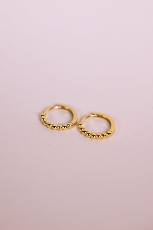 Gold bead hoop earrings on a neutral background