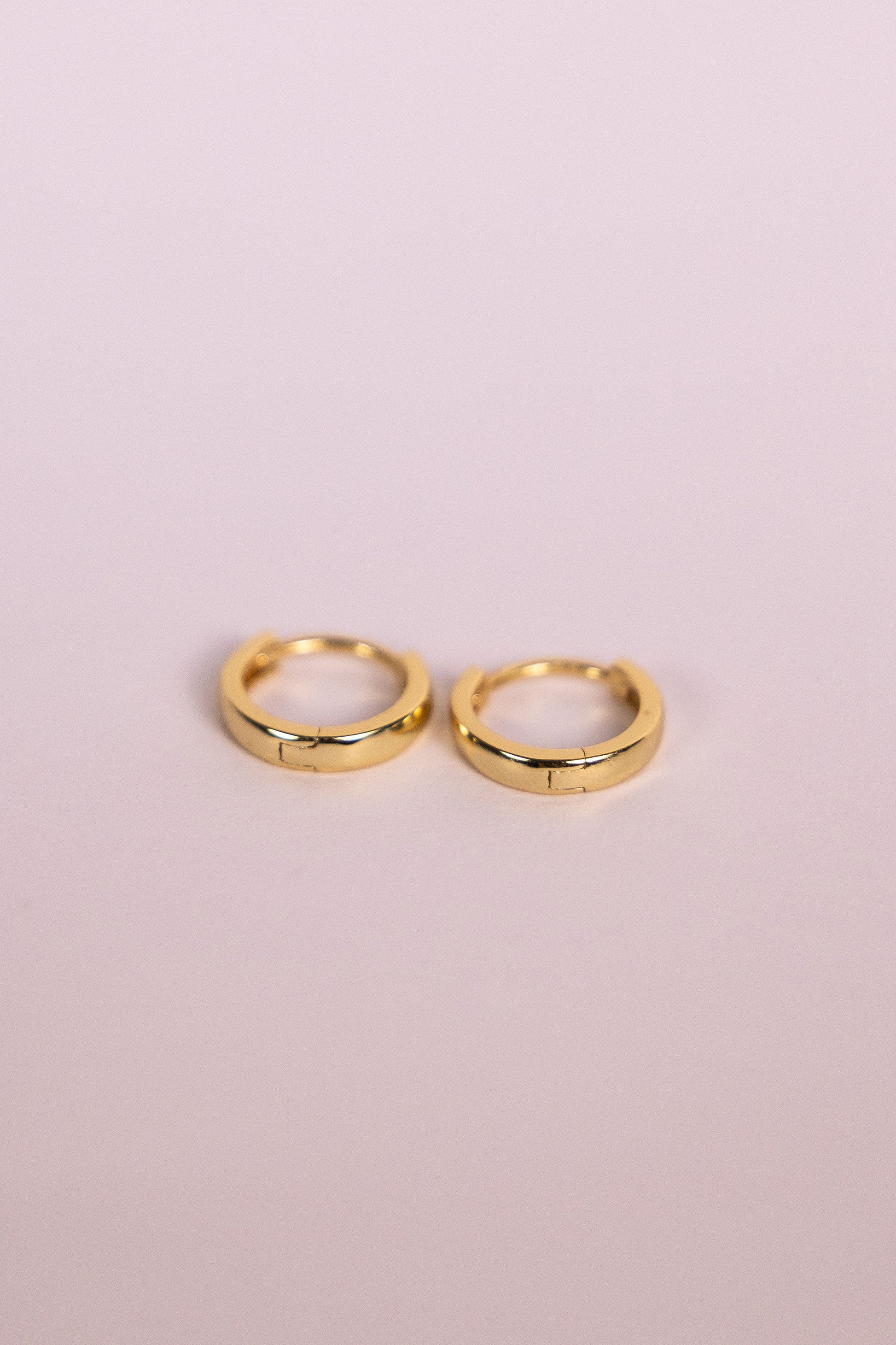 Gold hoop earrings on a neutral background