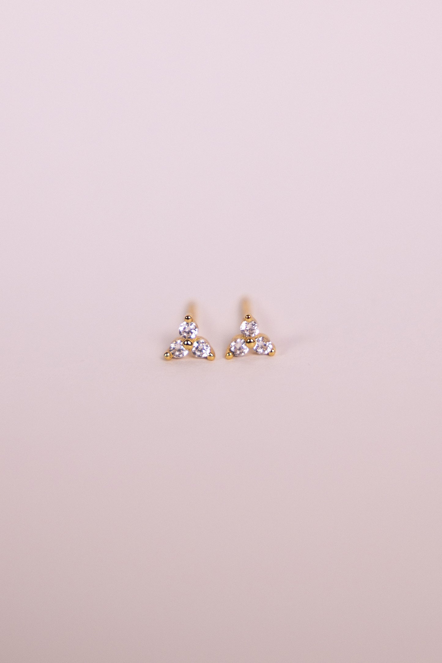 Pair of gold earrings with gemstones on a neutral background