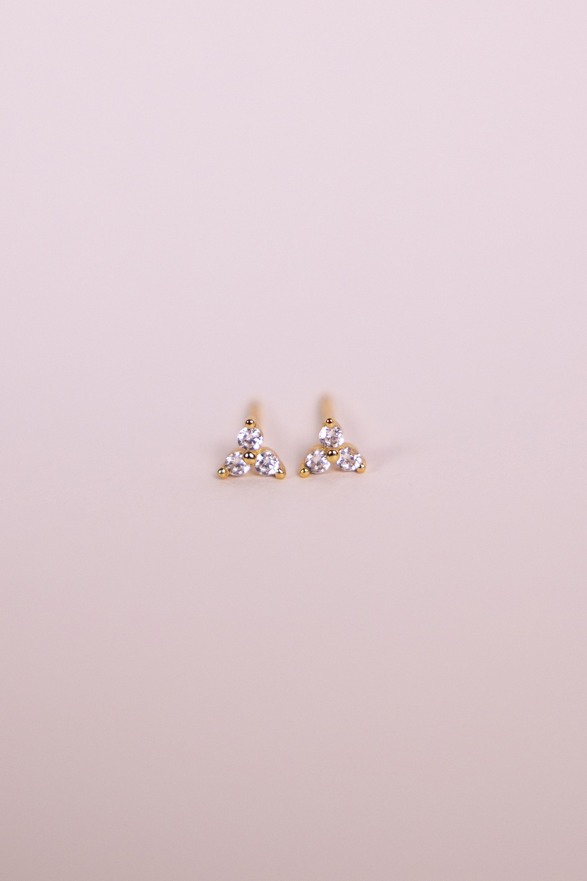 Pair of gold earrings with gemstones on a neutral background