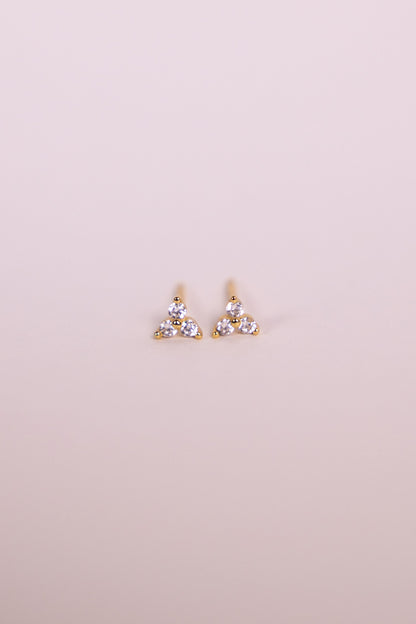 Pair of gold earrings with gemstones on a neutral background