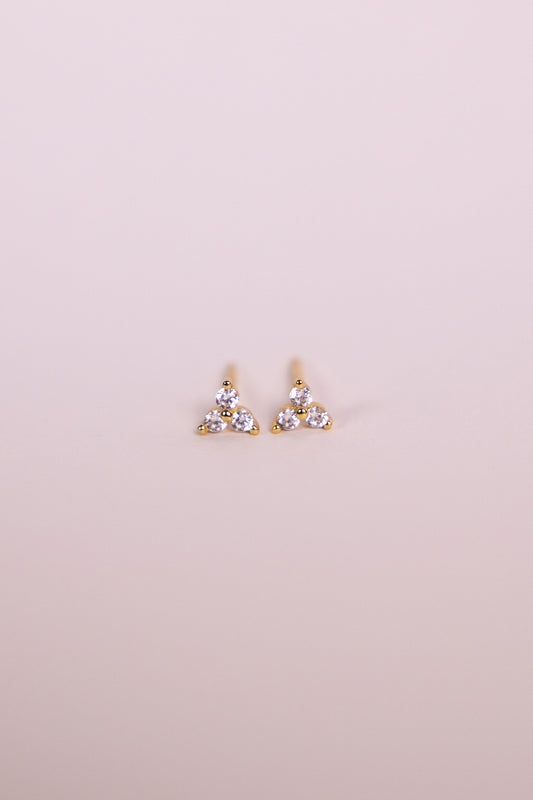 Pair of gold earrings with gemstones on a neutral background