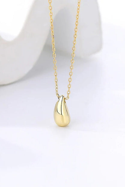 Gold necklace with a teardrop pendant on a white background